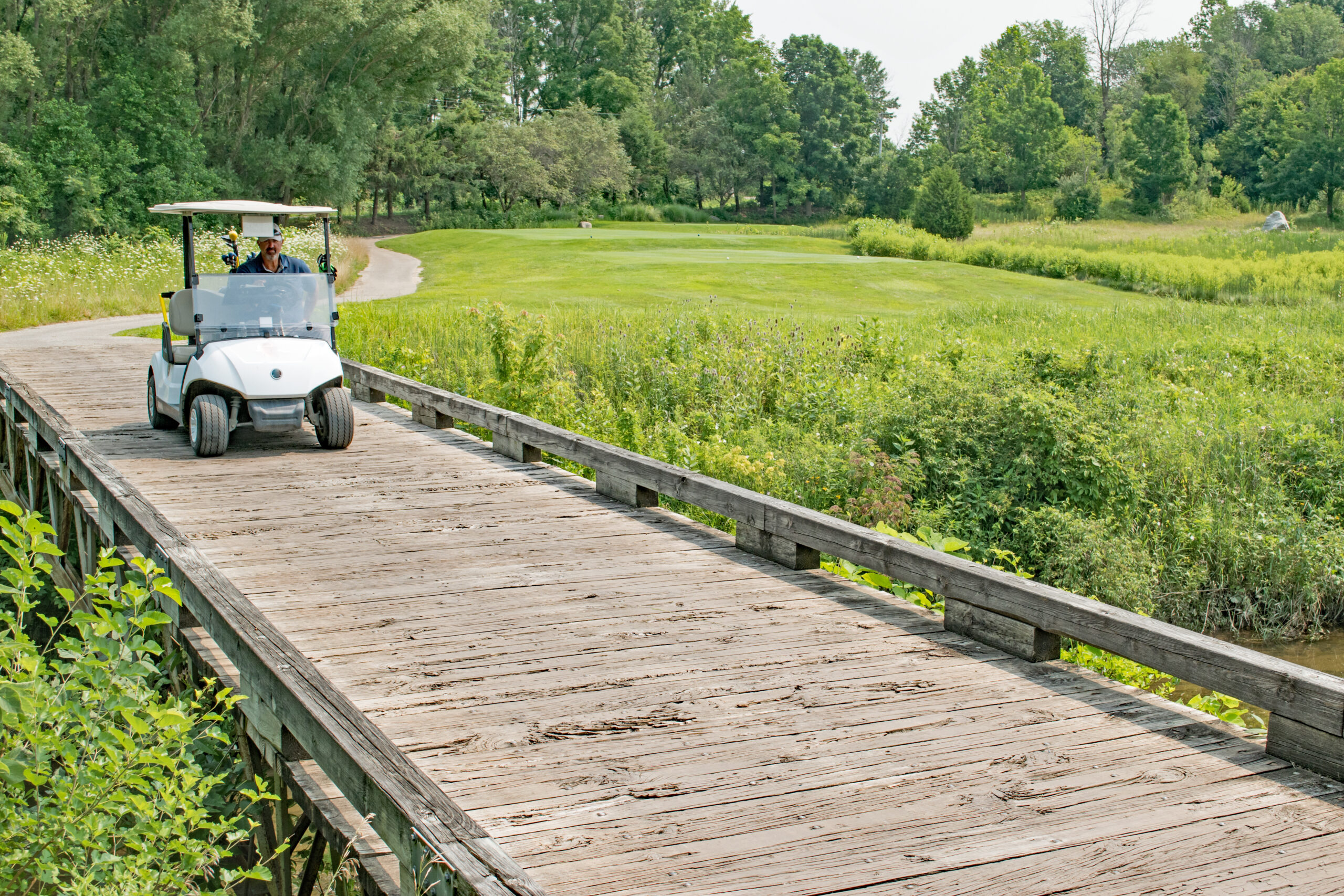 Golf cart crosses a bridge at a links course.